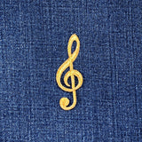 Gold treble clef symbol patch on blue denim fabric