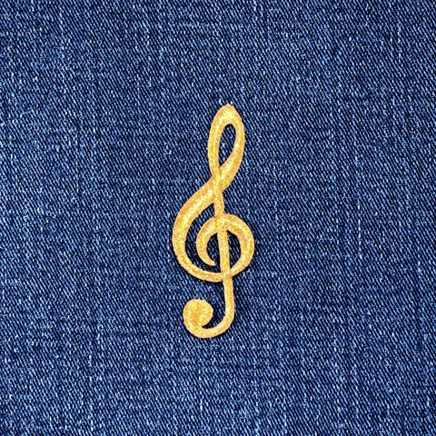 Gold treble clef symbol patch on blue denim fabric