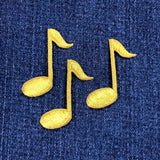 Three gold musical note patches on a blue denim background