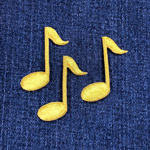 Three gold musical note patches on a blue denim background
