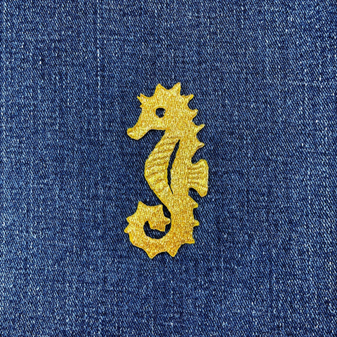 Gold seahorse patch on blue denim fabric