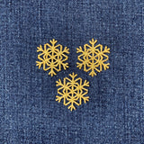 three gold snowflake patches on a denim background