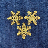 Three gold snowflake patches on a blue denim background