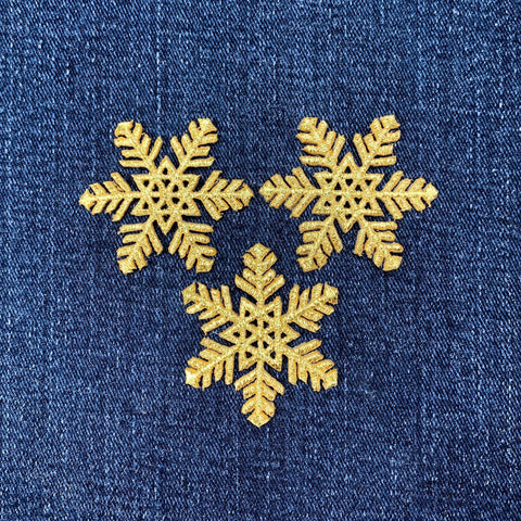 Three gold snowflake patches on a blue denim background