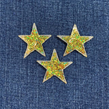 Three glittery gold star-shaped patches on a denim background