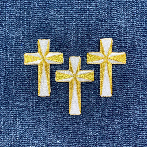 Three embroidered cross patches on a denim background