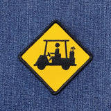 Embroidered patch of a yellow warning sign with a golf cart and golfer on a denim background