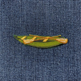 Embroidered green canoe patch on denim fabric