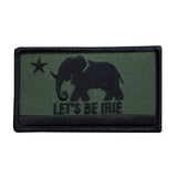 An embroidered rectangular patch featuring a black elephant silhouette, a black star, and the text 'LET'S BE IRIE' on an olive green background with a black border.