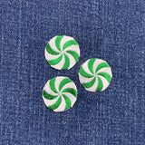 Three green and white peppermint candy patches on denim fabric