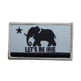 An embroidered rectangular patch featuring a black elephant silhouette, a black star, and the text 'LET'S BE IRIE' on a light gray background with a black horizontal stripe and gray stitched border.