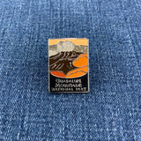 A pin badge featuring an illustration of Guadalupe Mountains National Park with a predominantly orange and black color scheme on a denim background