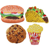 Four embroidered patches of food items arranged in a square: a hamburger on the top left, a hard-shell taco on the top right, a chocolate chip cookie on the bottom left, and a red and white striped bucket of popcorn on the bottom right.