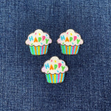 Three colorful cupcake patches with 'Happy' text on a denim background