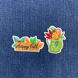 Two embroidered patches on denim fabric, one with 'Happy Fall' text and the other with a floral design.