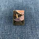 A pin with a graphic of Hawaii's Volcanoes National Park featuring artistic representations of Kilauea and Mauna Loa volcanoes on a denim background