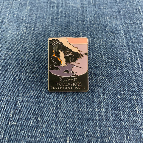 A pin with a graphic of Hawaii's Volcanoes National Park featuring artistic representations of Kilauea and Mauna Loa volcanoes on a denim background