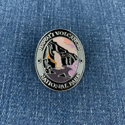 A round enamel Walking Stick Medallion featuring Hawaii Volcanoes National Park, displayed on a blue denim background.