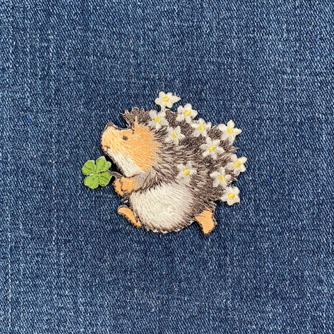 Embroidered hedgehog with flowers on denim fabric