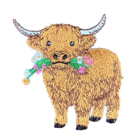 an embroidered patch of a Scottish highland cow with flowers in it's mouth on a white background