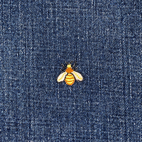 Embroidered bee patch on blue denim fabric