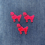 Three hot pink poodle-shaped patches on a denim background