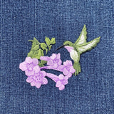 Embroidered patch of a hummingbird and flowers on denim fabric