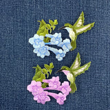 Embroidered patches of flowers and hummingbirds on a denim background