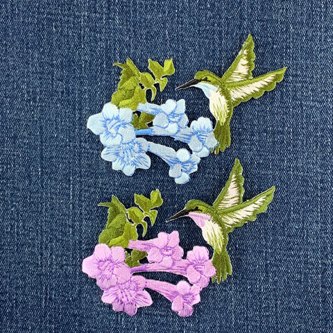 Embroidered patches of flowers and hummingbirds on a denim background