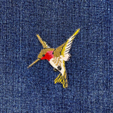 A patch depicting a green and red hummingbird facing left on a denim background