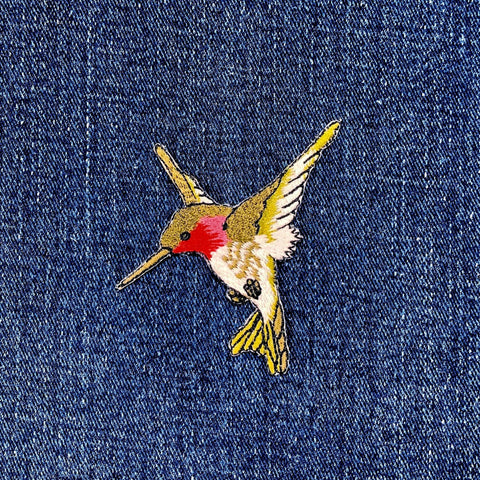 A patch depicting a green and red hummingbird facing left on a denim background