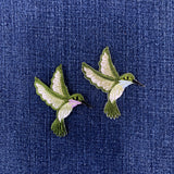 Two embroidered hummingbird patches on a denim background