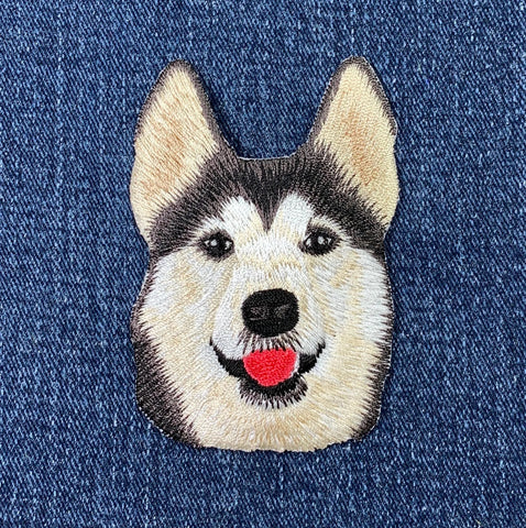 Embroidered patch of a husky dog's face on denim fabric