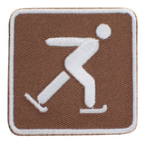 An embroidered square patch featuring a white icon of a person ice skating on a brown background with a white border.