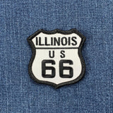 Illinois route 66 patch in the shape of a highway sign in black and white colors on a denim background.