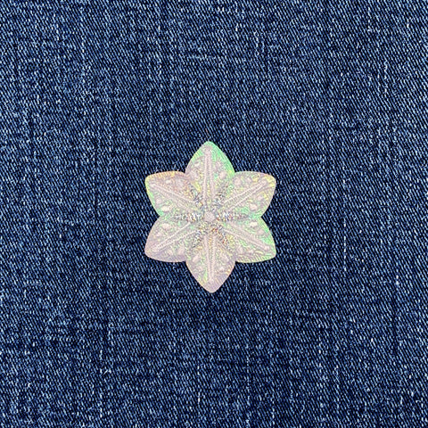 Snow-shaped iridescent patch on a denim background