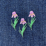 Embroidered purple iris flower patches on a denim fabric background