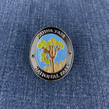 An oval enamel Walking Stick Medallion featuring the Joshua Tree National Park logo, displayed on a blue denim fabric background.