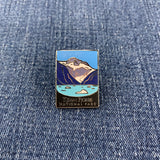 A pin badge featuring a mountain range with snow on the peaks, and the text 'Kenai Fjords National Park' on a denim background