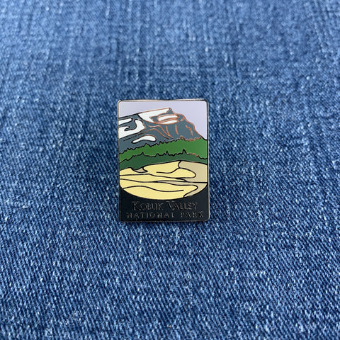 A pin featuring an illustration of a mountain range with the text 'Kobuk Valley National Park' at the bottom on a denim background