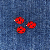 Three red ladybug patches on a denim background