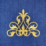 Gold decorative fleur de lis patch on a blue fabric background
