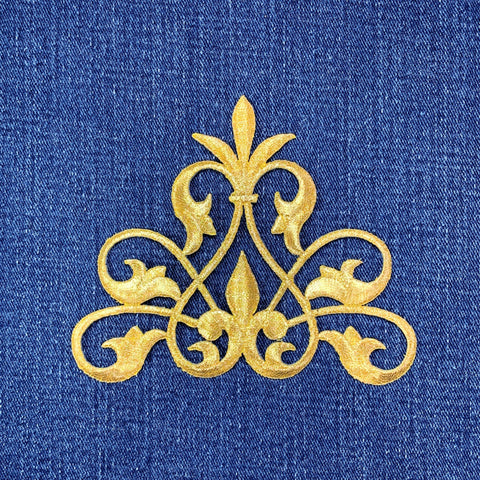 Gold decorative fleur de lis patch on a blue fabric background