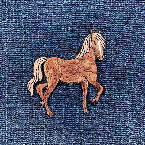 A brown horse applique patch with a realistic design on a denim background