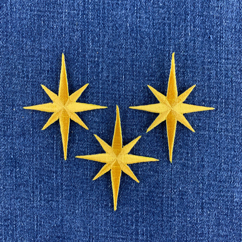 Three yellow star-shaped patches on a blue fabric background