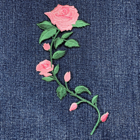 Embroidered pink rose patch on a blue denim fabric