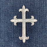 Decorative silver cross patch on denim fabric