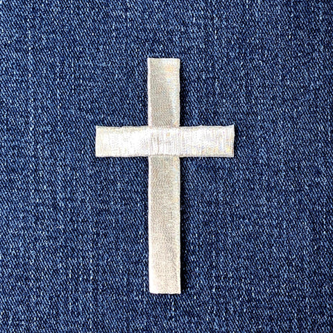 a silver cross patch on a denim background