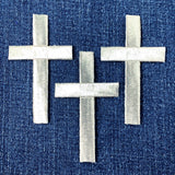three silver cross patches on a denim background