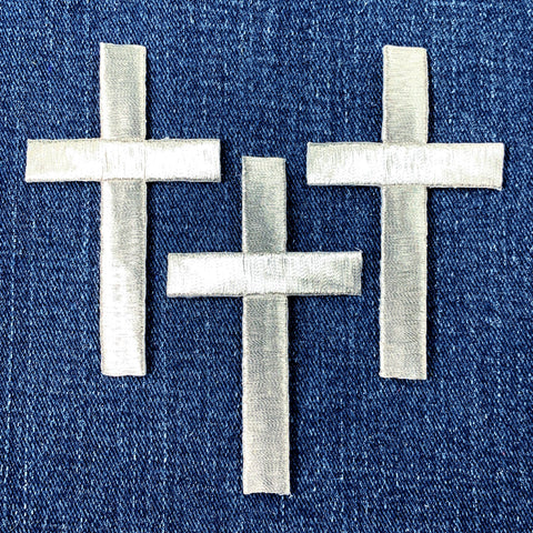 three silver cross patches on a denim background